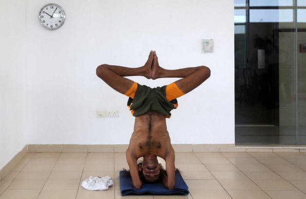 Ivan Stanley, a 41 year-old Indian man attempts to breaks the world’s record for holding a headstand during celebrations of World Yoga Day, in Dubai, United Arab Emirates, Sunday, June 21, 2015. Stanley held the position for 61 minutes and registered his attempt with the Guinness World Records, which has yet to announce if he broke the record. Photo: Kamran Jebreili, AP / AP