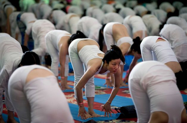 Chinese perform yoga at a hotel banquet hall to mark the International Yoga Day, in Changping District, on the outskirts of Beijing, China, Sunday, June 21, 2015. Yoga enthusiasts bent and twisted their bodies in complex postures across India and much of the world on Sunday to mark the first International Yoga Day. Photo: Andy Wong, AP / AP
