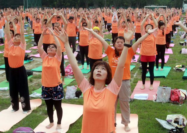 Taiwanese perform yoga poses at the start of International Yoga Day in Taipei, Taiwan, June 21, 2015. Equipped with yoga mats and humming the sounds of Om, over two thousand people in Taipei city performed the 108 rounds of the Sun Salutation Sunday marking the start of the International Yoga Day in a Taipei university’s soccer field. Photo: Chiang Ying-ying, AP / AP